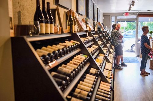 A wine shop interior with shelves of wine bottles and customers browsing.