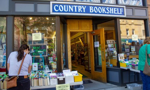 A cozy bookstore entrance with a sign reading "Country Bookshelf" and displays of books outside.