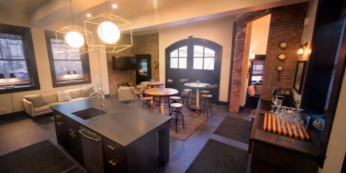 Modern kitchen and dining area with a large island, wooden accents, and stylish lighting in a cozy, open layout.