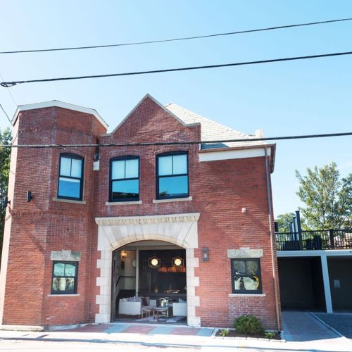 A red brick building with large windows and a welcoming entrance, set against a clear blue sky.