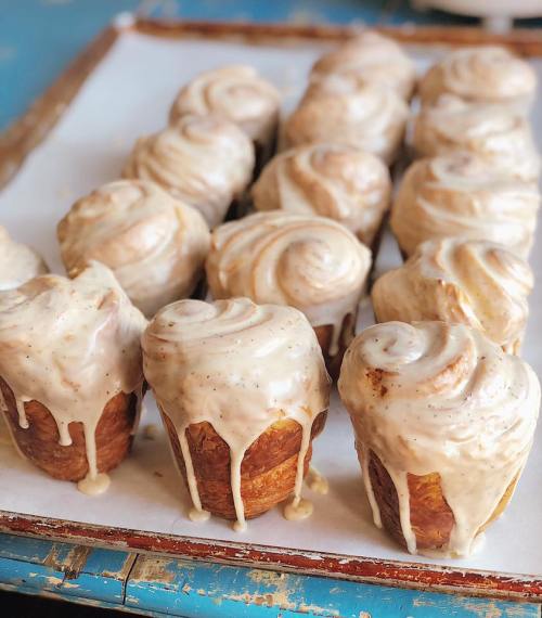 A tray of freshly baked cinnamon rolls with creamy icing, arranged in neat rows on parchment paper.