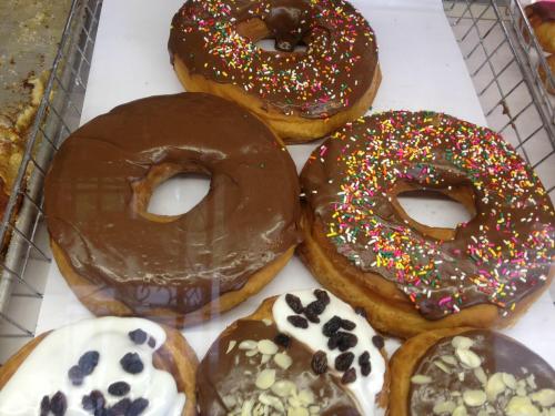 A display of donuts: two chocolate frosted with sprinkles, and two with white frosting topped with raisins and nuts.