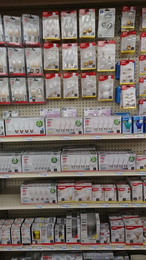 A store display featuring various types of light bulbs in packaging on shelves.