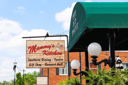 Sign for "Mammy's Kitchen" featuring Southern dining, a gift shop, and banquet hall, set against a blue sky.