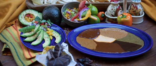 A vibrant spread of colorful ingredients, including avocado, vegetables, and various sauces on a purple plate.