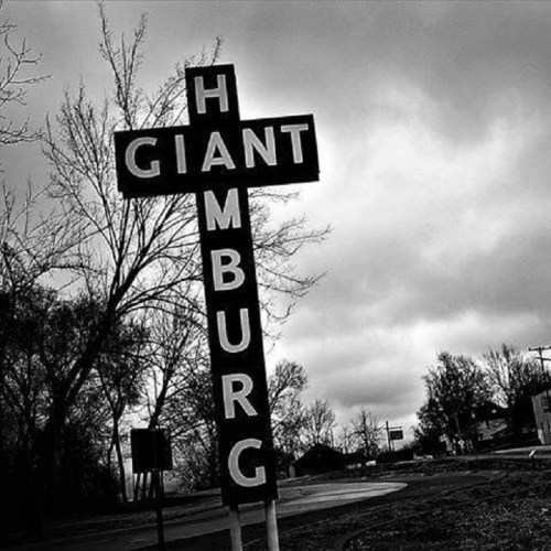 A large, vintage sign reading "GIANT HAMBURG" against a cloudy sky, surrounded by bare trees.