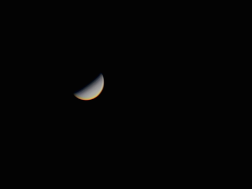 A crescent moon illuminated against a dark sky, showcasing its curved shape and subtle color gradient.