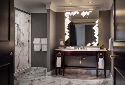 Luxurious bathroom featuring marble floors, a stylish sink, modern lighting, and a spacious shower area.