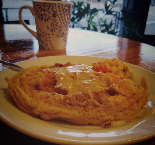 A plate of fluffy omelette topped with cheese, served with a patterned coffee mug in the background.
