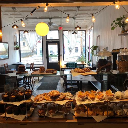 A cozy bakery display with various pastries and cookies, featuring a warm interior and string lights.