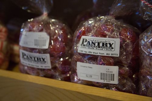 Bags of cinnamon disks candy on a shelf, labeled with price and store information.