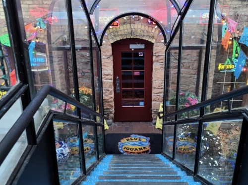 A staircase leading down to a colorful entrance with neon signs and decorative lights.