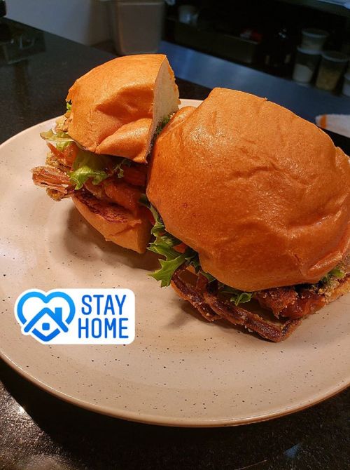 Two delicious sandwiches with lettuce on a plate, accompanied by a "Stay Home" logo in the corner.
