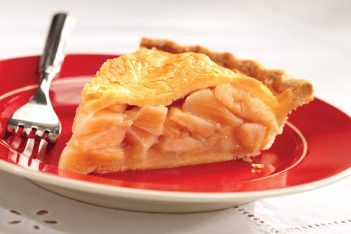 A slice of apple pie on a red plate, showcasing a golden crust and visible apple filling, with a fork beside it.