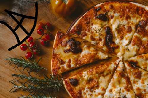 A freshly baked pizza with melted cheese, sliced, surrounded by cherry tomatoes and rosemary on a wooden surface.