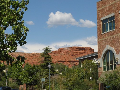 View of a rocky hillside with the word "DIXIE" displayed, framed by trees and a building in the foreground.