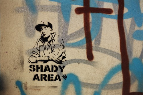 A graffiti mural featuring a man in a cap with the text "SHADY AREA" beside him, set against colorful background splashes.