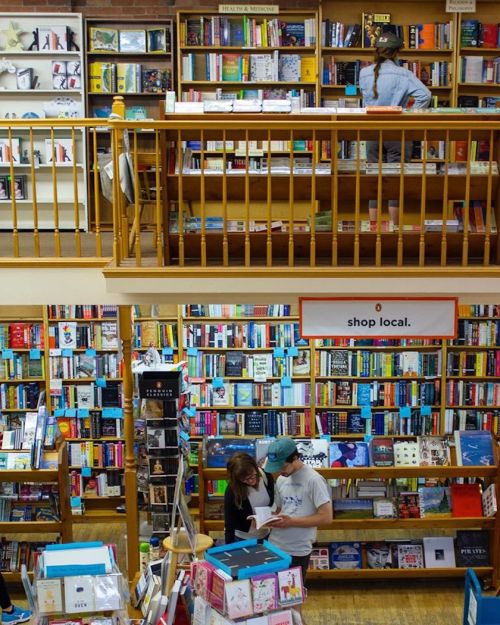 A cozy bookstore with two levels, featuring shelves filled with colorful books and two people browsing together.
