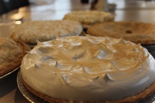 A close-up of several pies with meringue topping, arranged on a table.