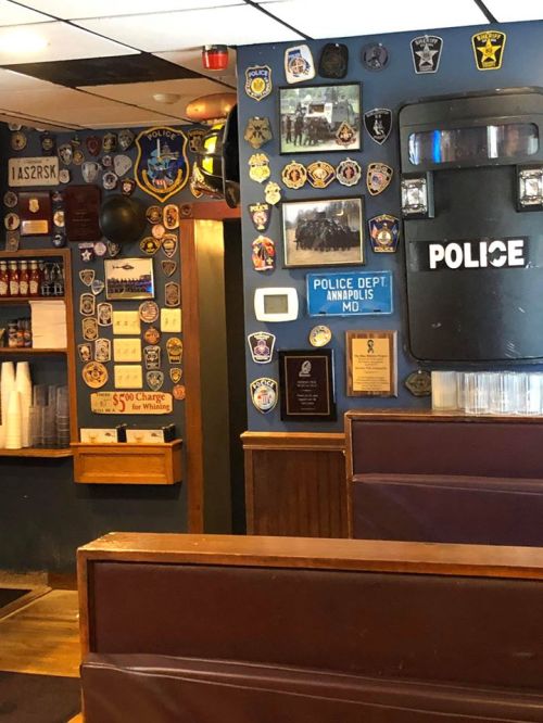 Interior of a restaurant featuring a wall adorned with various police badges and memorabilia.