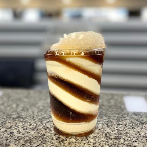 A cup of swirled vanilla and chocolate ice cream topped with a layer of ice, set on a countertop.
