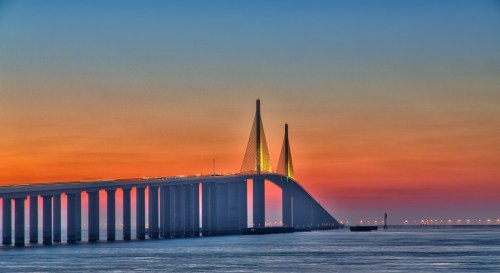 A striking bridge at sunset, with vibrant colors reflecting on the water below.