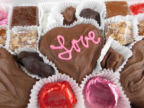 A box of assorted chocolates, featuring a heart-shaped chocolate with "Love" written in pink icing.