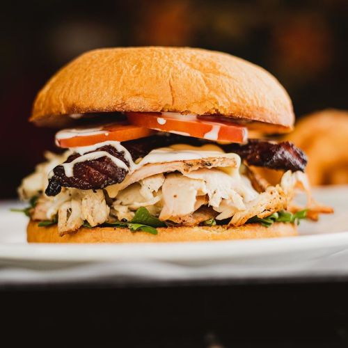 A close-up of a delicious sandwich with grilled chicken, bacon, lettuce, tomato, and mayonnaise on a toasted bun.