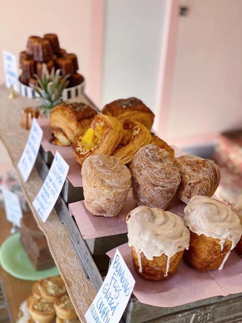 A display of assorted pastries, including glazed buns, croissants, and cinnamon rolls, on a rustic table.