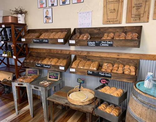 A cozy bakery display with wooden shelves filled with various baked goods and chalkboard labels.