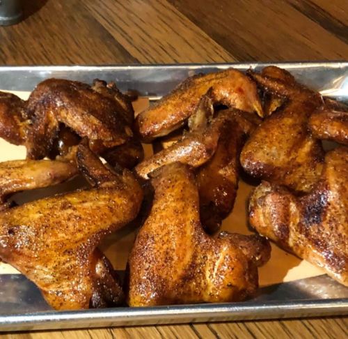 A platter of golden-brown, seasoned chicken wings arranged on a metal tray.