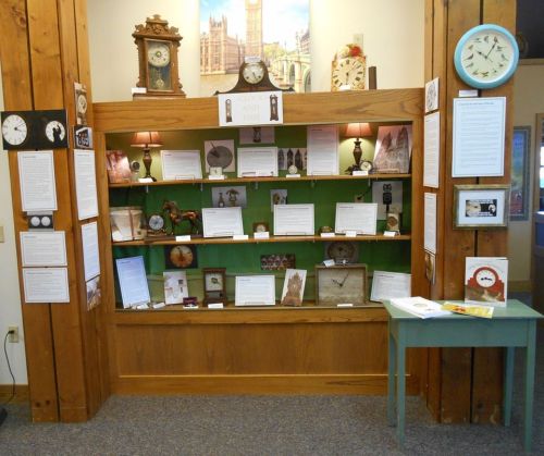 Display of clocks and time-related artifacts in a museum exhibit, featuring information panels and decorative elements.