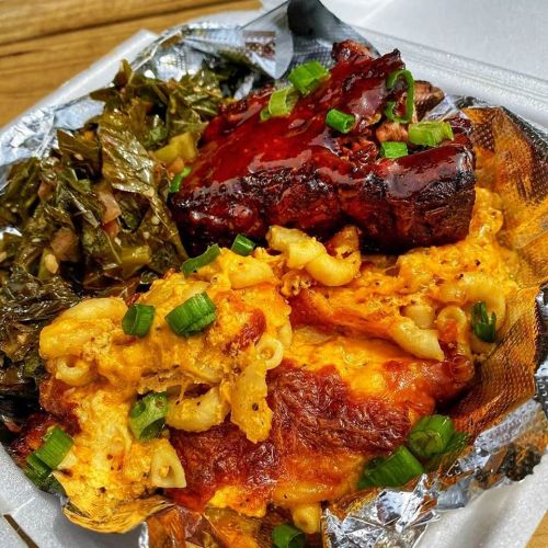A plate featuring barbecue ribs, macaroni and cheese, and collard greens, garnished with green onions.