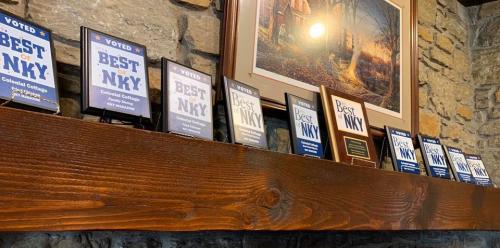 A wooden shelf displaying multiple awards and plaques labeled "Voted Best of NKY" against a stone wall backdrop.