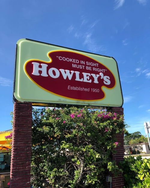 Sign for Howley's restaurant with the slogan "Cooked in sight must be right," established in 1950, surrounded by greenery.