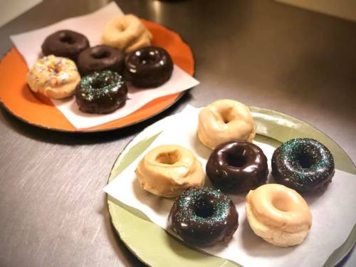 A plate of assorted donuts, including chocolate, glazed, and sprinkled varieties, on a countertop.
