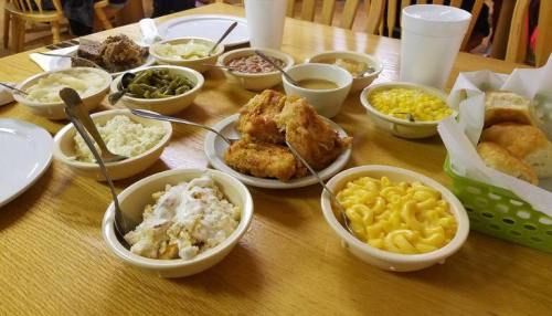 A table filled with various dishes, including fried chicken, macaroni and cheese, green beans, and biscuits.