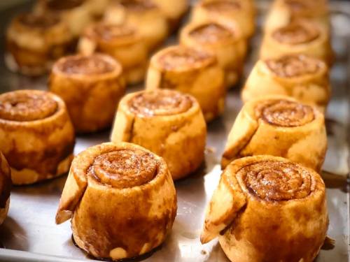 Freshly baked cinnamon rolls arranged on a tray, showcasing their golden-brown color and spiral design.