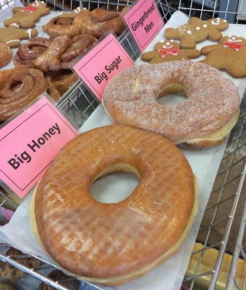 A display of donuts labeled "Big Honey," "Big Sugar," and gingerbread men in a bakery.