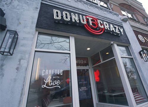 Exterior of Donut Crazy shop featuring a sign and large windows with "Crafted with Love" displayed.
