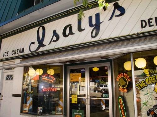 A vintage ice cream shop with a sign reading "Isaly's" and neon lights advertising hot dogs and coffee.