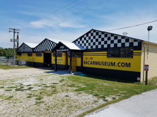 Exterior of a car museum with a checkered pattern, featuring a yellow and black color scheme and a website address.
