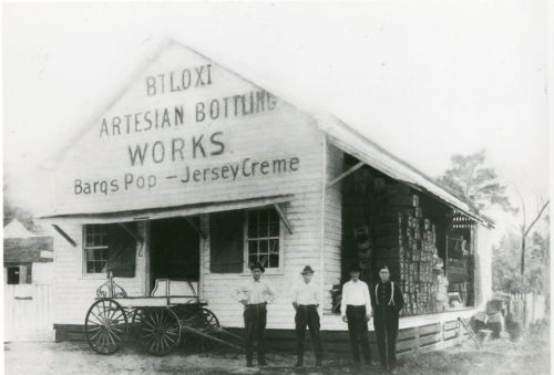 Historic black-and-white photo of Biloxi Artesian Bottling Works with four men standing in front of the building.