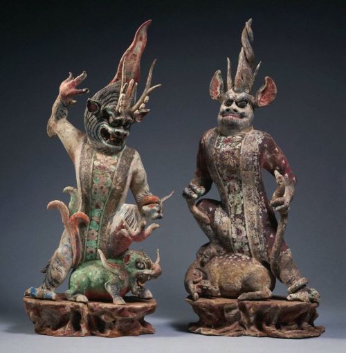 Two ornate, mythical creature sculptures with intricate details, depicting fierce figures atop smaller animals.