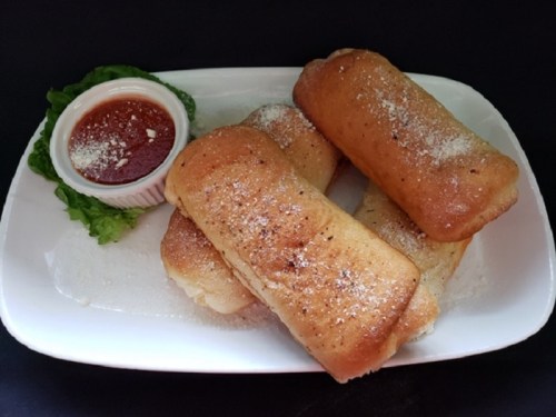 Three golden-brown stuffed rolls on a plate, sprinkled with powder, served with a side of red sauce and lettuce.