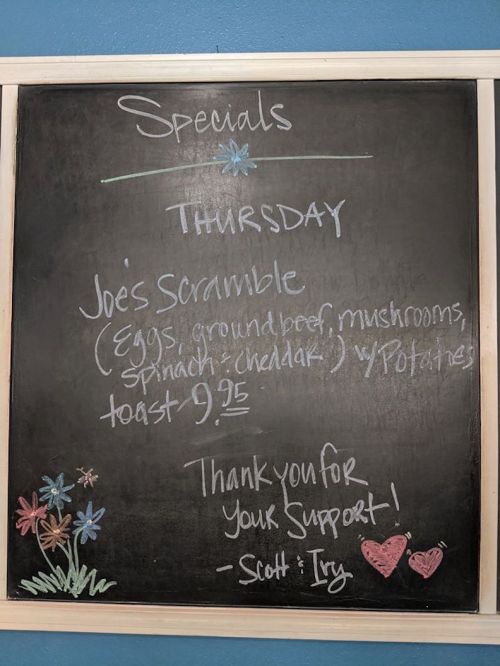 Chalkboard menu listing Thursday special: Joe's Scramble with eggs, ground beef, mushrooms, spinach, cheddar, and toast.