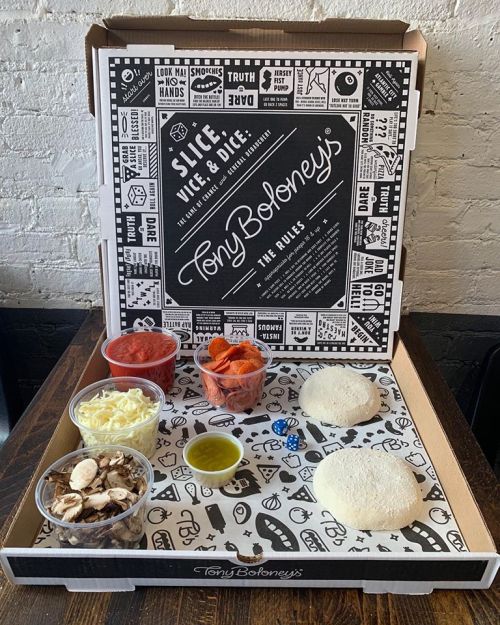 A pizza kit from Tony Boloney's with dough, toppings, sauce, and a game die in a decorative box.
