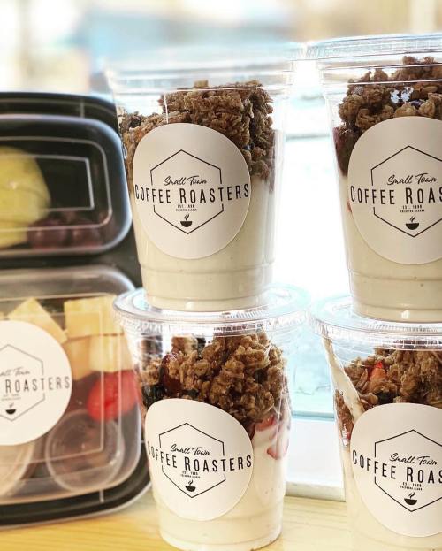 Four cups of yogurt parfaits topped with granola, next to a container of fresh fruit, all branded with "Small Town Coffee Roasters."