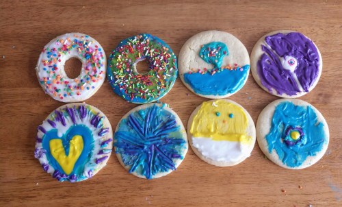 A variety of decorated cookies with colorful icing and sprinkles arranged on a wooden surface.