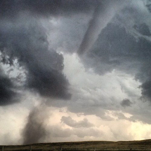 A dramatic sky with dark storm clouds and a visible funnel cloud forming in the distance.